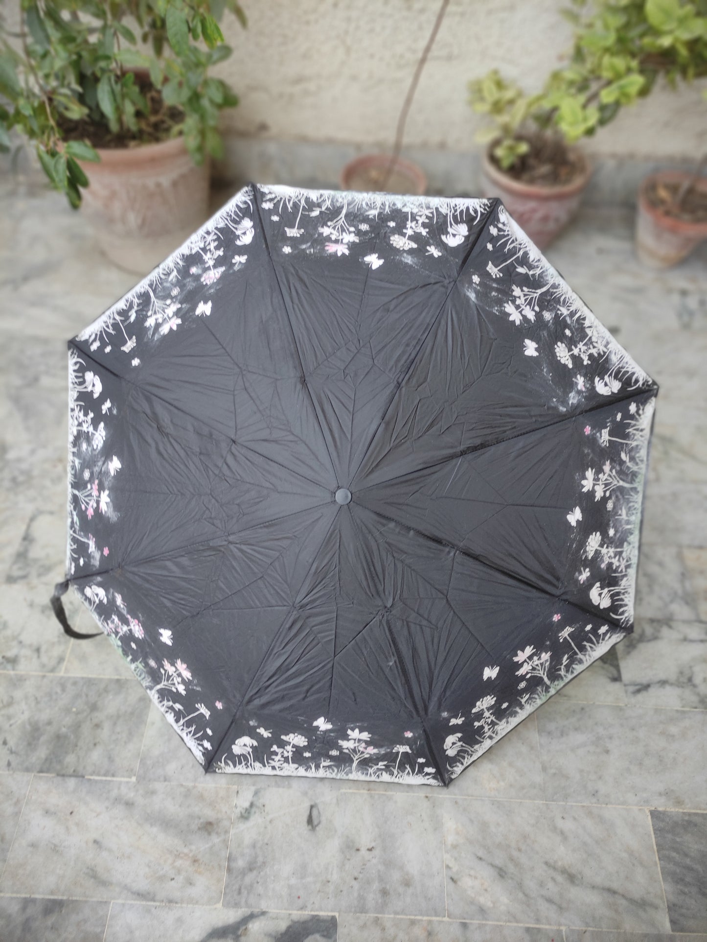 BLACK FOLDING UMBRELLA WITH A WHITE FLORAL AND BUTTERFLY PATTERN